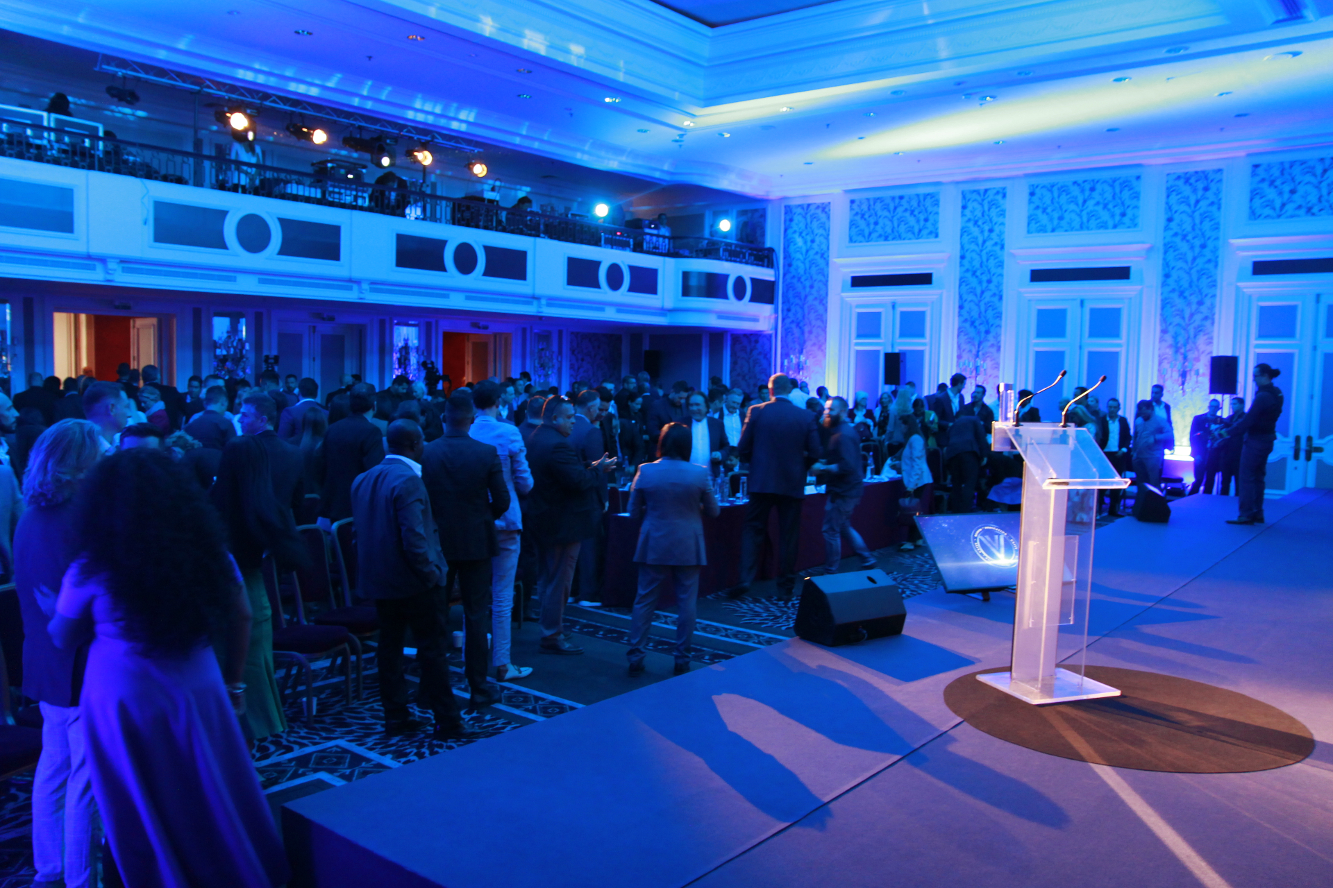 Gala corporativa en hotel de lujo · iluminación azul y atril iluminado con público